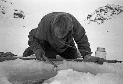Jim Stammers collecting specimens through hole in ice